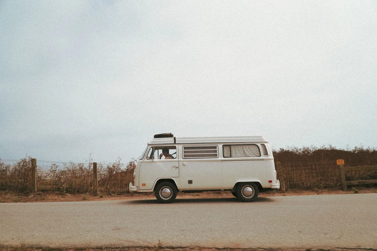 Weißer VW Bus in Seitenansicht am Straßenrand
