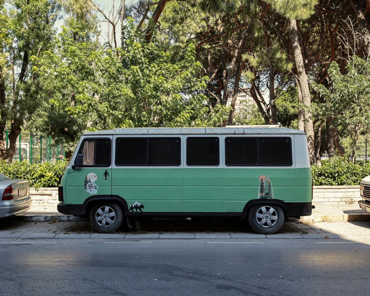 Campervan parkt am Straßenrand einer baumbestandenen Stadtstraße