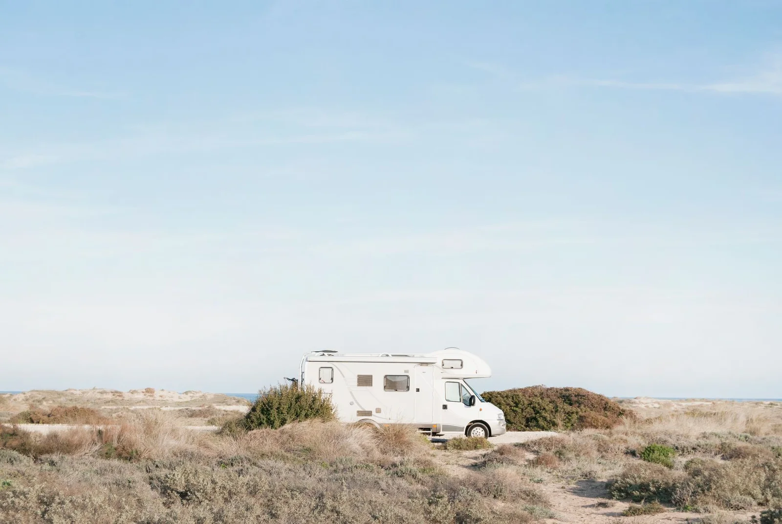 Wohnmobil bei Tageslicht in heller Dünenlandschaft, symbolisch für die richtige Camper-Ausbau-Reihenfolge