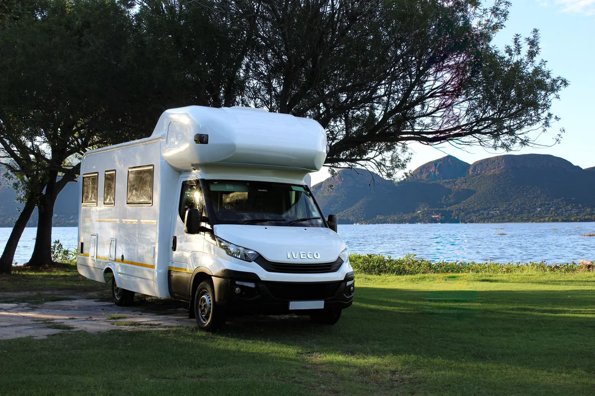 Moderner Campervan auf einer hellen Wiese an einem See