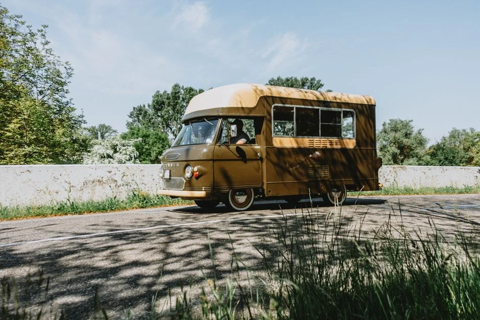Brauner Volkswagen Campervan auf einer sonnigen Landstraße