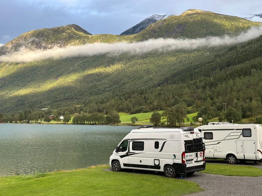 Campervans an einem See vor einer hellen Bergkulisse