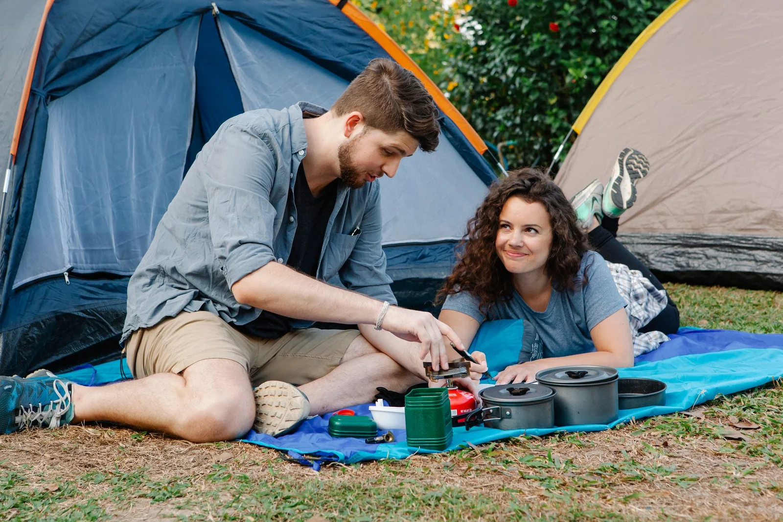 Paar bereitet gemeinsam eine Mahlzeit beim Camping im Wald zu, entspannter Campingalltag im Freien