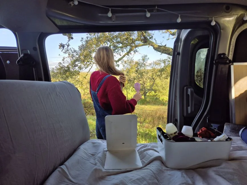 Lose Aufbewahrungsboxen auf der Liegefläche eines Camper Vans mit geöffneten Hecktüren