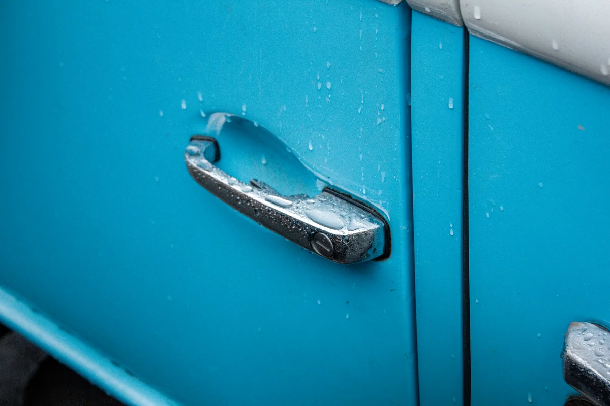 Detailaufnahme eines Türgriffs am Camper mit Regentropfen