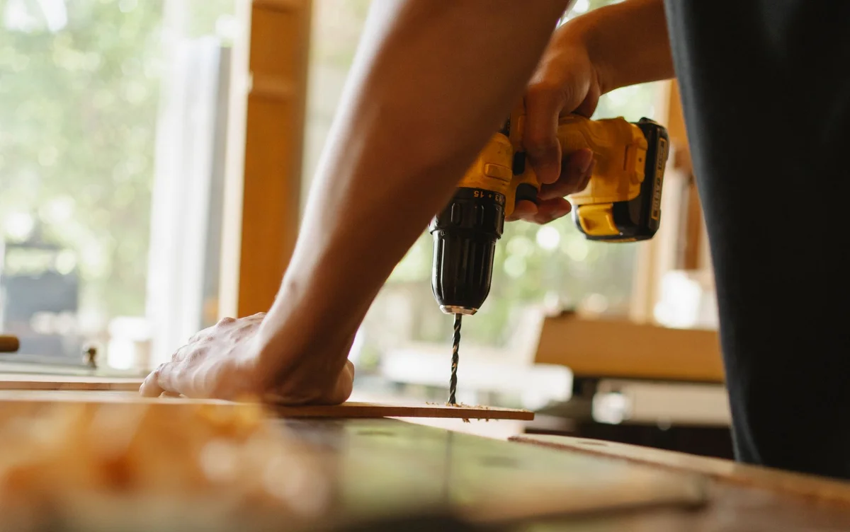 Handwerker bohrt eine Holzplatte in der Werkstatt
