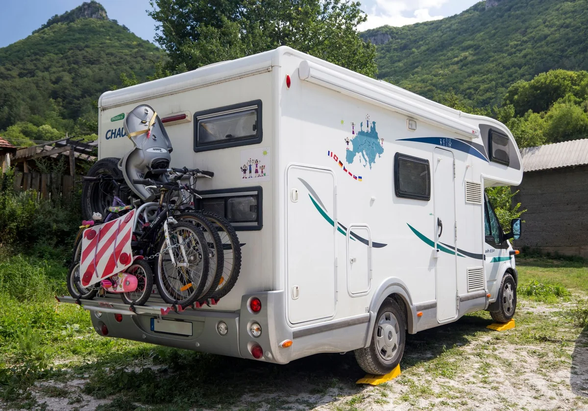 Wohnmobil mit zwei Fahrrädern auf einem Heckträger vor einer Bergkulisse