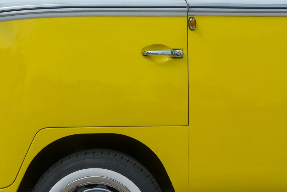Nahaufnahme der gelben Seitenwand und Schiebetür eines VW Transporters