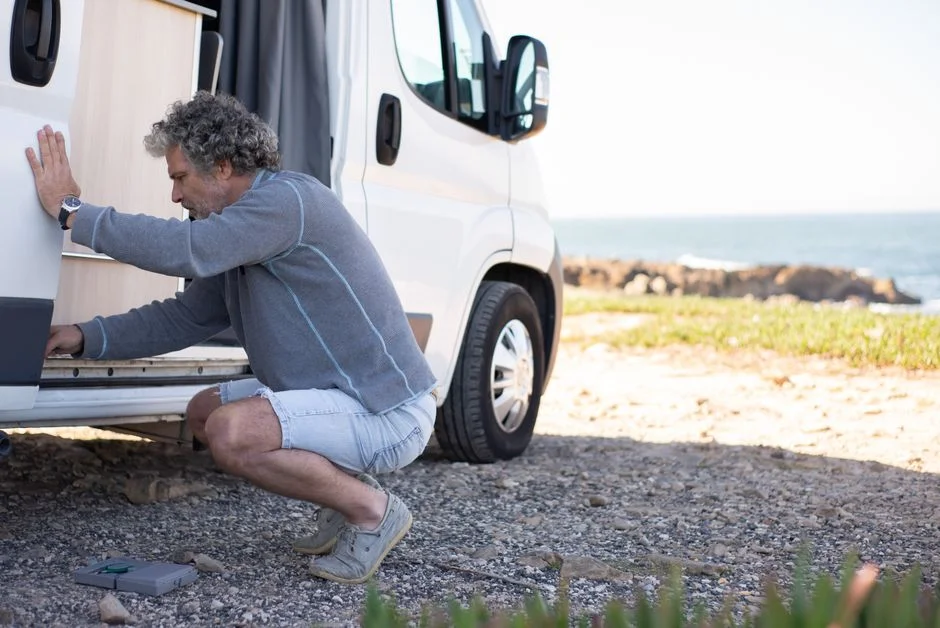 Geöffneter Camper mit sichtbarem Innenausbau an einem hellen Küstenplatz