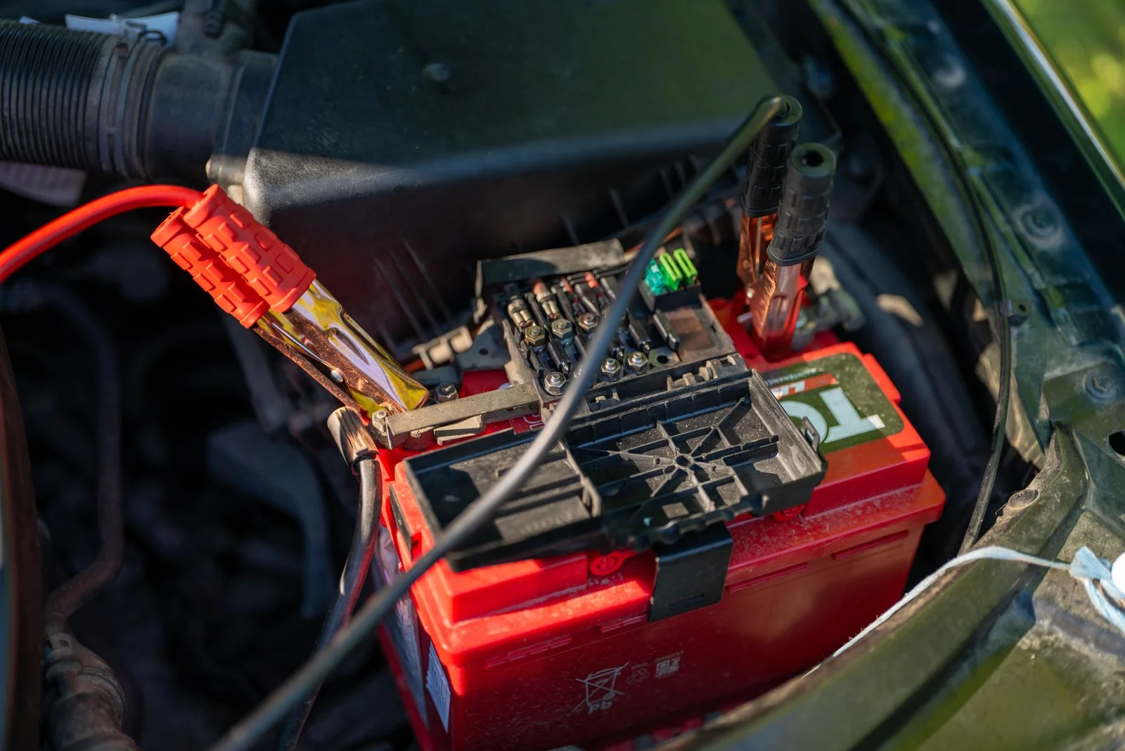 Autobatterie mit angeschlossenen roten Kabeln