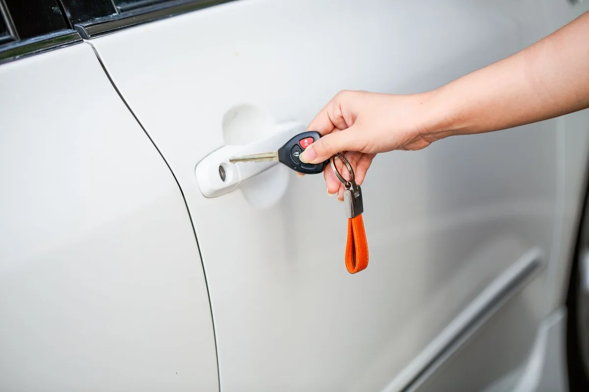 Hand mit Fahrzeugschlüssel an weißer Autotür – Keyless-Entry und Schlüsselschutz beim VW T6