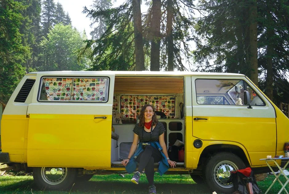 Van mit geöffneter Schiebetür auf einem Stellplatz im Wald