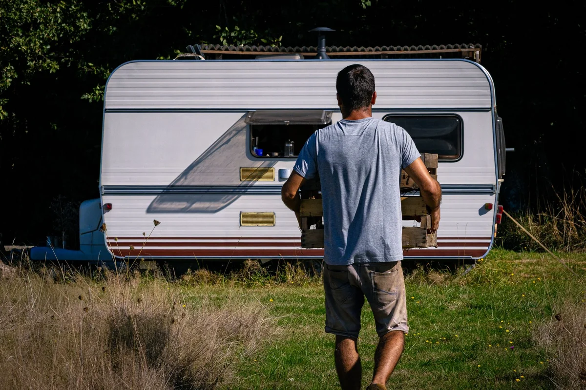 Person trägt eine Kiste neben einem Caravan