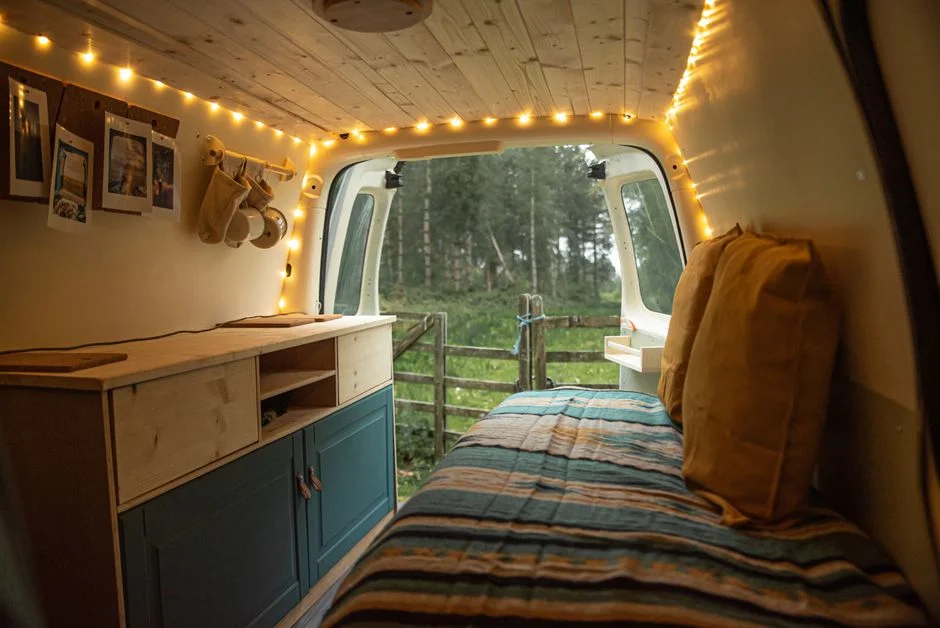 Gemütliche Bettnische im Innenraum eines Campingfahrzeugs mit Blick ins Grüne